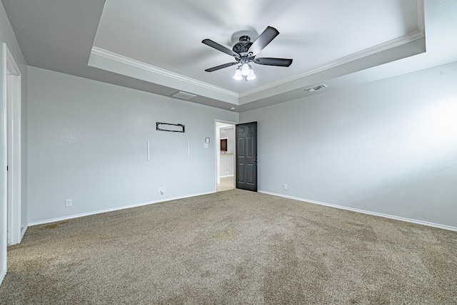 carpeted spare room with crown molding, baseboards, ceiling fan, and a tray ceiling