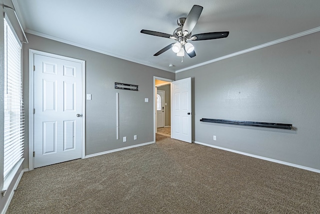 unfurnished bedroom featuring carpet floors, baseboards, crown molding, and ceiling fan