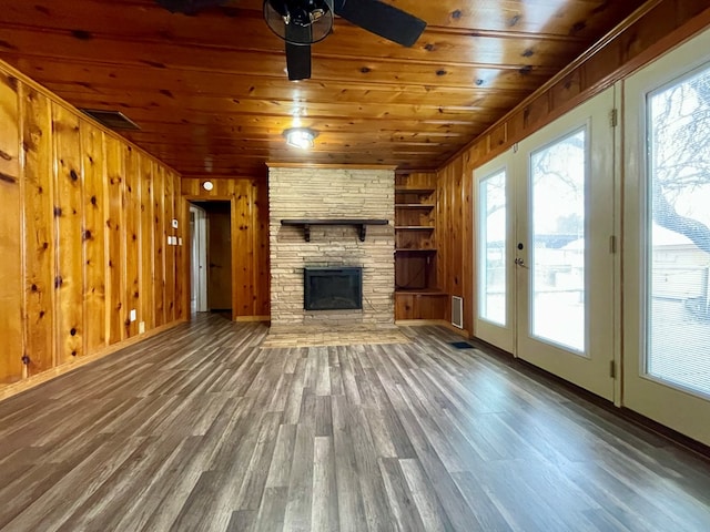 2508 31st St, Snyder, TX 79549 - unfurnished living room featuring wood ceiling, ceiling fan, wood-type flooring, a stone fireplace, and wood walls