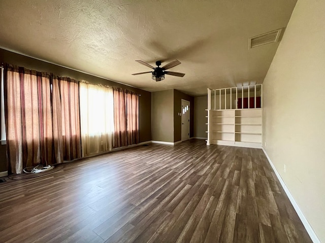 unfurnished living room featuring ceiling fan, dark hardwood / wood-style floors, and a textured ceiling