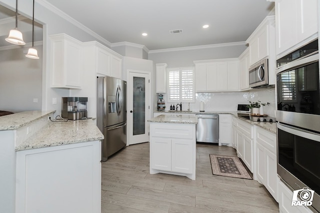 kitchen with light stone counters, white cabinets, stainless steel appliances, and decorative light fixtures