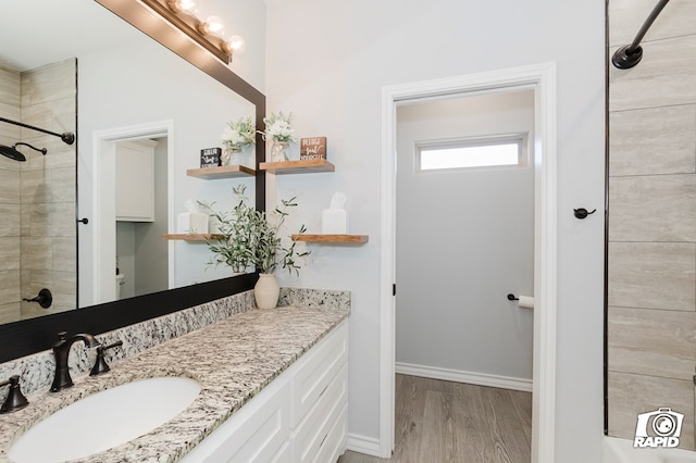 bathroom with a tile shower, vanity, and hardwood / wood-style flooring