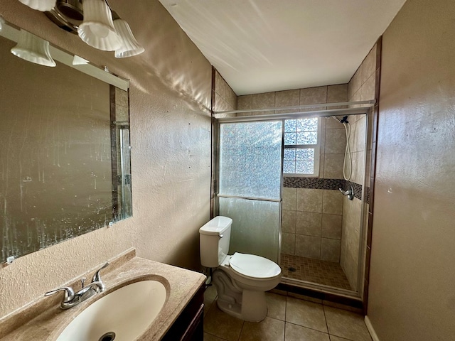 full bath featuring toilet, vanity, tile patterned flooring, a textured wall, and a shower stall