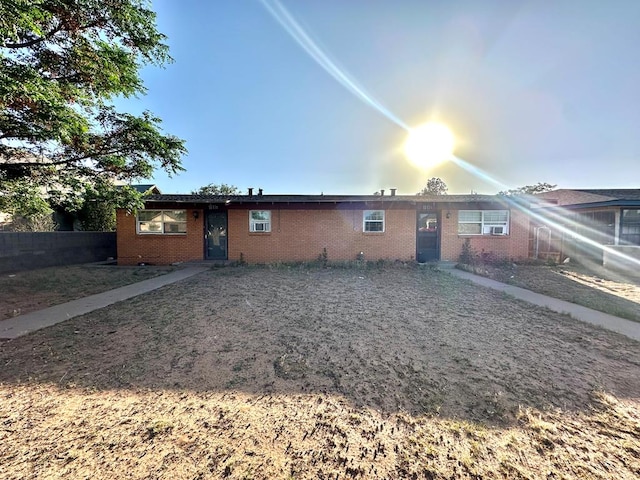 rear view of house featuring brick siding and fence