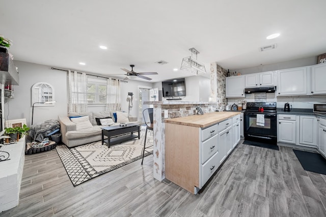 kitchen featuring visible vents, under cabinet range hood, black range with electric cooktop, open floor plan, and wooden counters