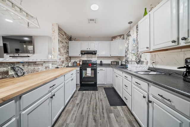 kitchen with electric range, visible vents, under cabinet range hood, white cabinetry, and decorative backsplash