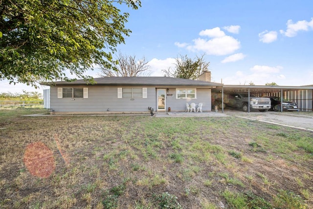 ranch-style house with a carport, a chimney, and a front lawn