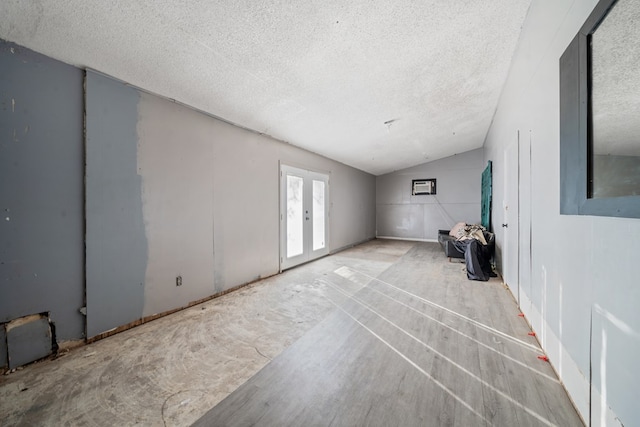 empty room with vaulted ceiling, french doors, and a textured ceiling