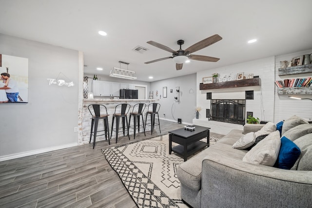 living area with wood finished floors, baseboards, a fireplace, recessed lighting, and ceiling fan