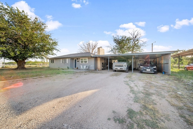 single story home featuring a carport, a chimney, and dirt driveway