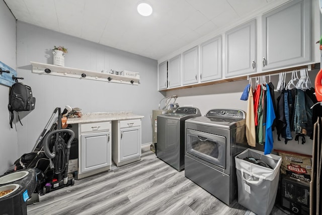 laundry area featuring washing machine and clothes dryer, cabinet space, and light wood finished floors