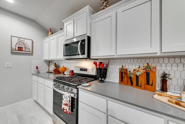 kitchen featuring white cabinets, vaulted ceiling, appliances with stainless steel finishes, and tasteful backsplash