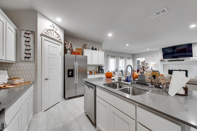 kitchen with a fireplace, stainless steel appliances, white cabinets, and sink