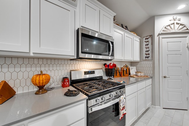 kitchen with tasteful backsplash, white cabinets, and stainless steel appliances