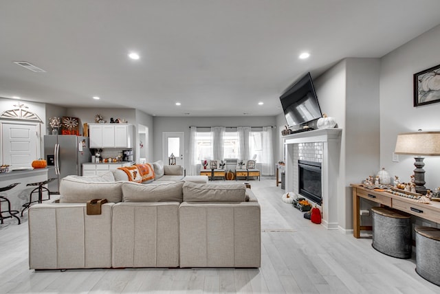 living room featuring light hardwood / wood-style flooring and a tiled fireplace