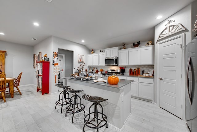 kitchen with backsplash, a kitchen breakfast bar, white cabinetry, and stainless steel appliances