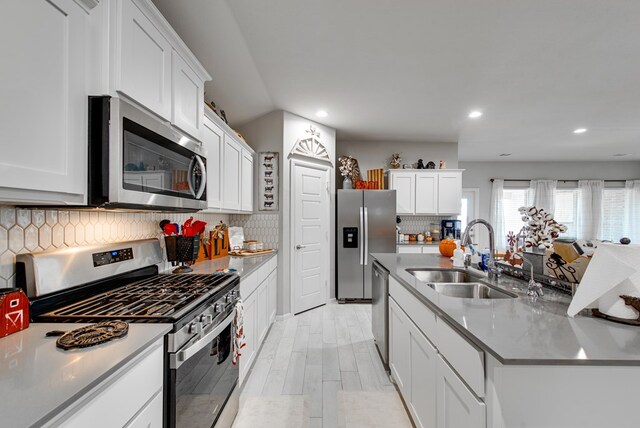 kitchen with white cabinets, backsplash, stainless steel appliances, and sink