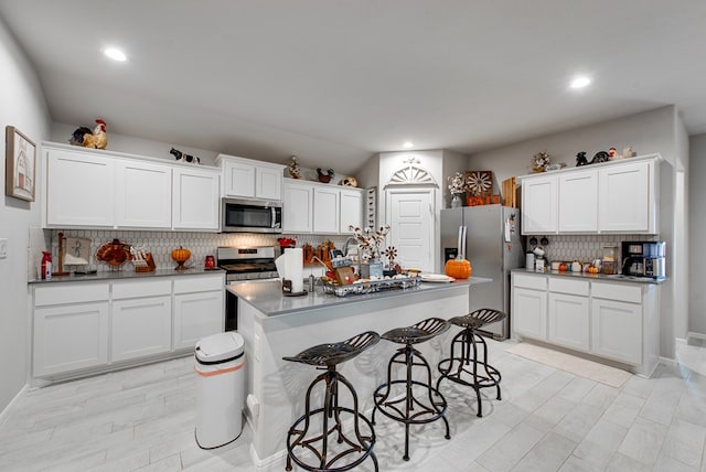 kitchen with backsplash, white cabinetry, a breakfast bar, and stainless steel appliances