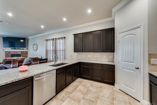 kitchen with stainless steel dishwasher, dark brown cabinets, a sink, and backsplash