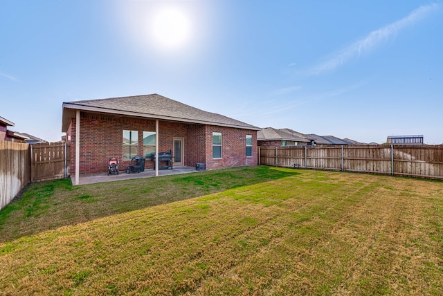 back of property featuring a fenced backyard, brick siding, a patio, and a lawn