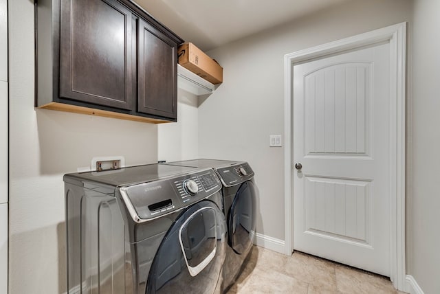 laundry room with baseboards, cabinet space, and washer and clothes dryer