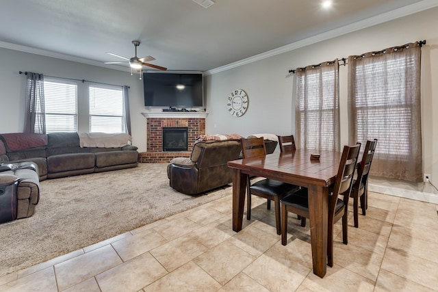 dining space featuring ceiling fan, light tile patterned floors, light colored carpet, ornamental molding, and a brick fireplace