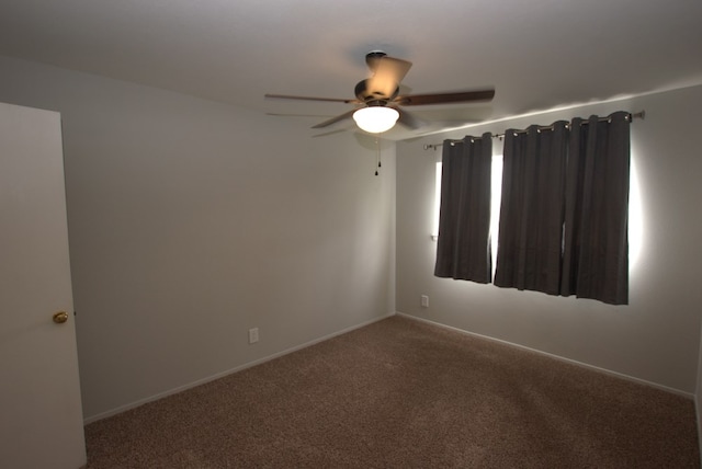 carpeted spare room featuring a ceiling fan and baseboards