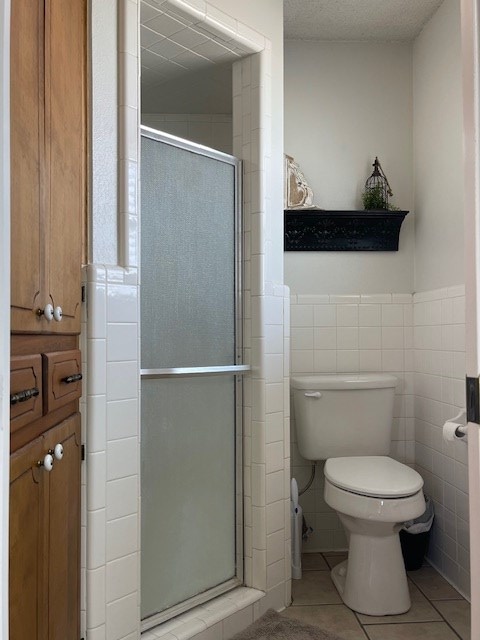 4500 El Paso, Snyder, TX 79549 - full bath with tile patterned floors, a shower stall, tile walls, and wainscoting