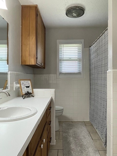 4500 El Paso, Snyder, TX 79549 - full bath featuring tile walls, tile patterned flooring, vanity, healthy amount of natural light, and curtained shower