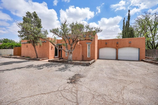 2309 W Golf Course Rd, Midland, TX 79701 - pueblo revival-style home with driveway, fence, and an attached garage