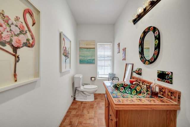 2309 W Golf Course Rd, Midland, TX 79701 - bathroom with stone finish flooring, vanity, toilet, and baseboards