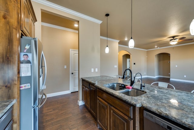 kitchen featuring stainless steel appliances, a sink, arched walkways, dark wood-style floors, and a ceiling fan