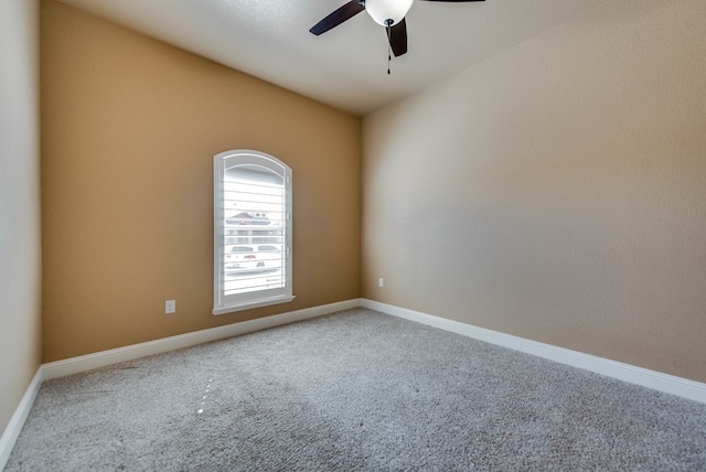 carpeted empty room with a ceiling fan and baseboards