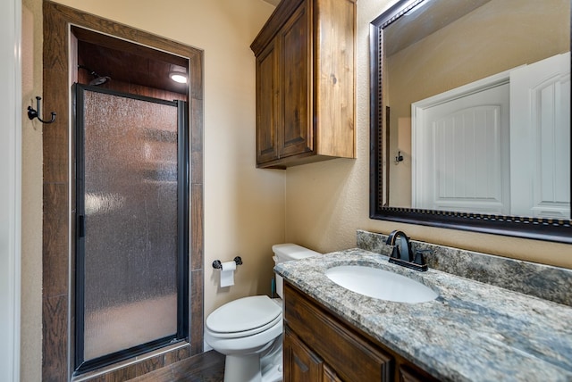 full bath featuring toilet, a stall shower, and vanity