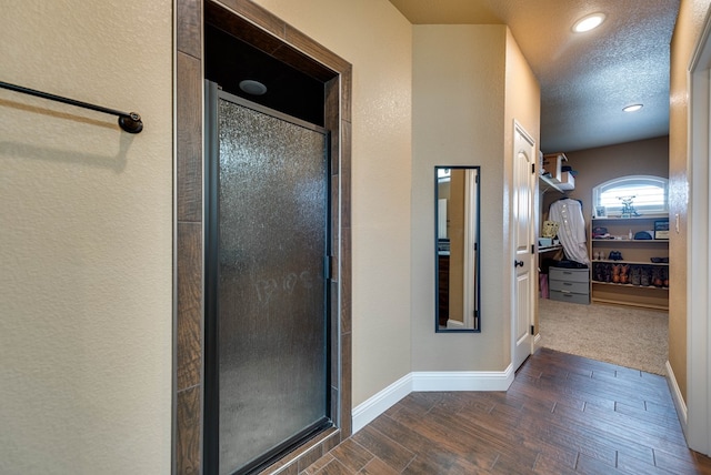 full bathroom featuring baseboards, a textured ceiling, wood finished floors, and a shower stall
