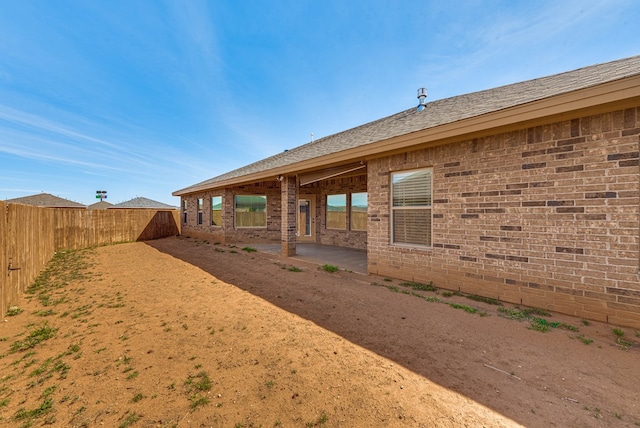back of property featuring a fenced backyard, brick siding, and a patio area