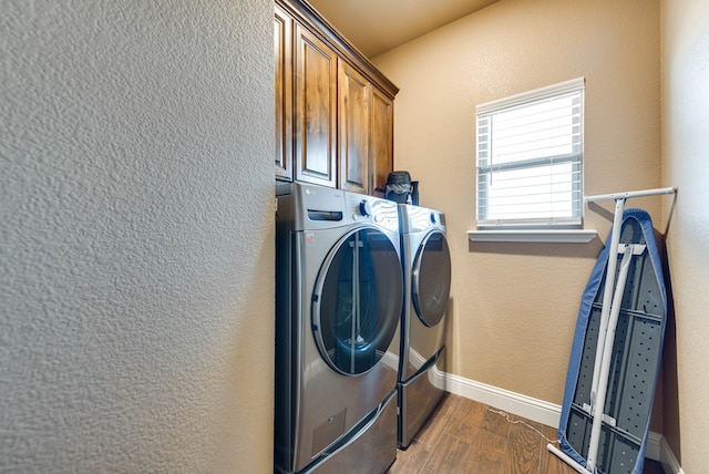 laundry area with baseboards, independent washer and dryer, cabinet space, a textured wall, and dark wood-style flooring