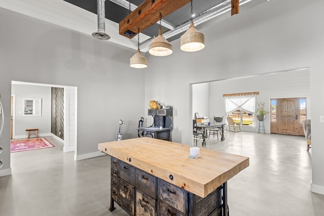 kitchen with beamed ceiling, a towering ceiling, and hanging light fixtures