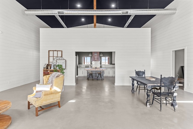 dining space with high vaulted ceiling and concrete flooring