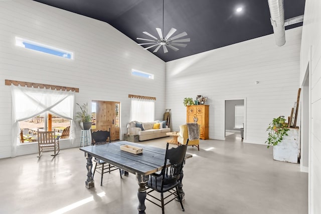 interior space featuring a chandelier, high vaulted ceiling, and concrete flooring