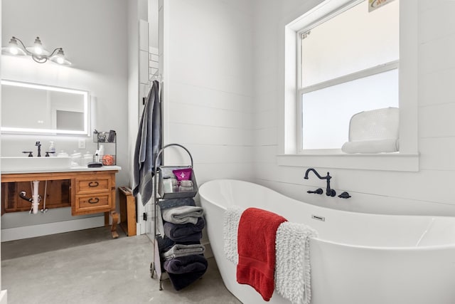 bathroom with a tub, vanity, and concrete flooring