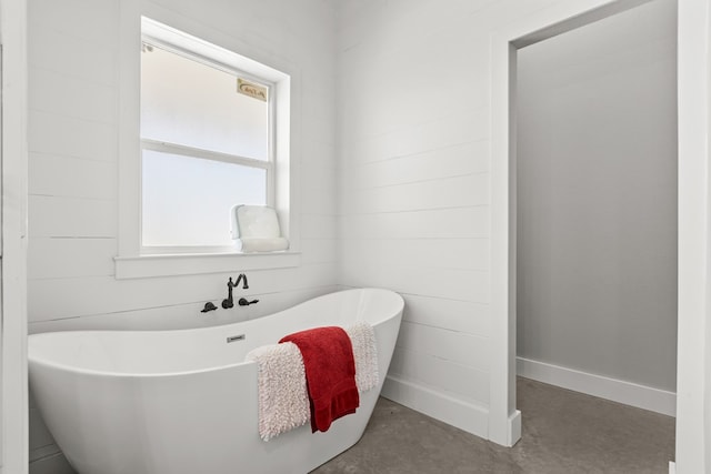 bathroom with a washtub and concrete flooring