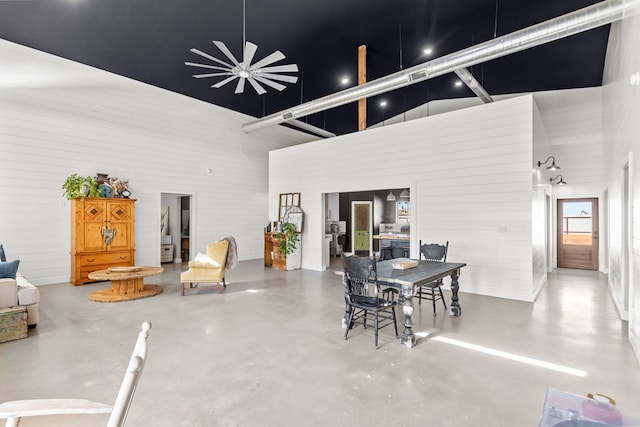 dining room with high vaulted ceiling and concrete flooring