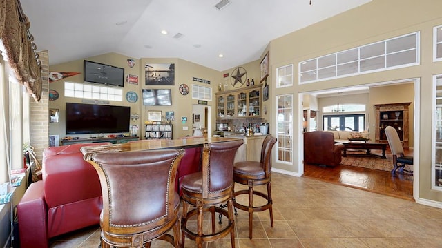 bar featuring visible vents, tile patterned flooring, bar area, and high vaulted ceiling