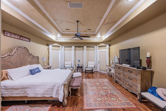 bedroom featuring crown molding, a raised ceiling, and wood finished floors