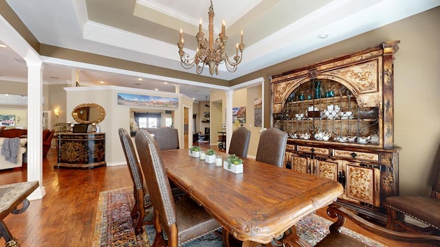 dining area featuring crown molding, ornate columns, a notable chandelier, and wood finished floors