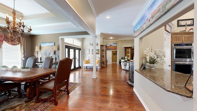 dining space featuring an inviting chandelier, recessed lighting, wood finished floors, ornate columns, and ornamental molding