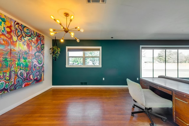 home office with dark wood-type flooring and an inviting chandelier