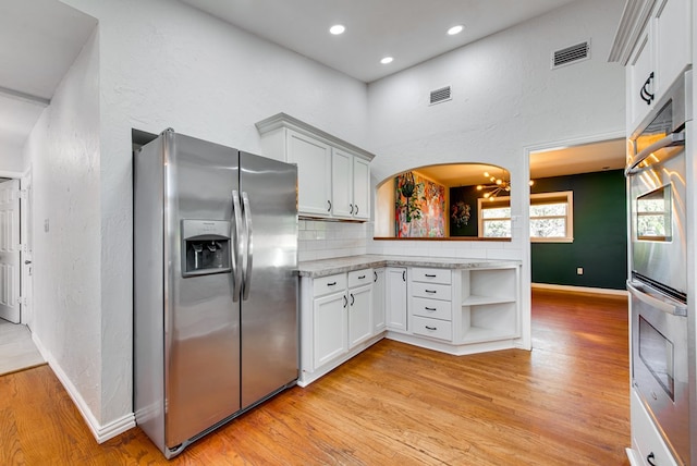 kitchen with white cabinetry, decorative backsplash, light hardwood / wood-style flooring, and stainless steel appliances