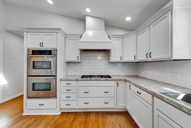 kitchen featuring stainless steel appliances, light hardwood / wood-style flooring, custom range hood, and white cabinets